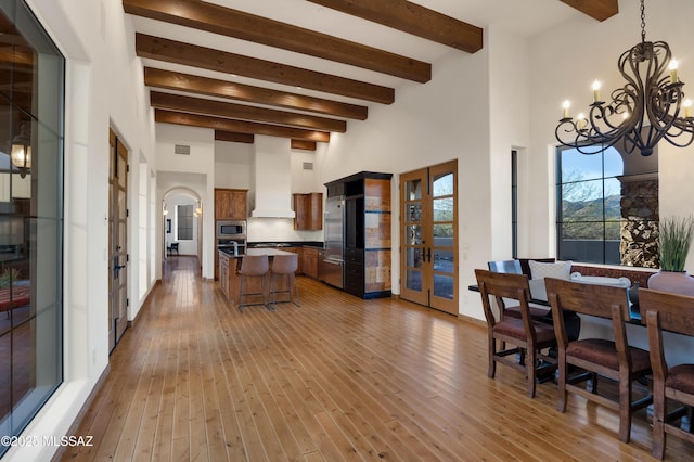 kitchen featuring a kitchen island, a kitchen breakfast bar, built in appliances, light wood-style floors, and premium range hood