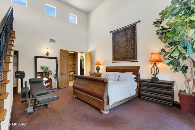 bedroom with a high ceiling, visible vents, and dark carpet