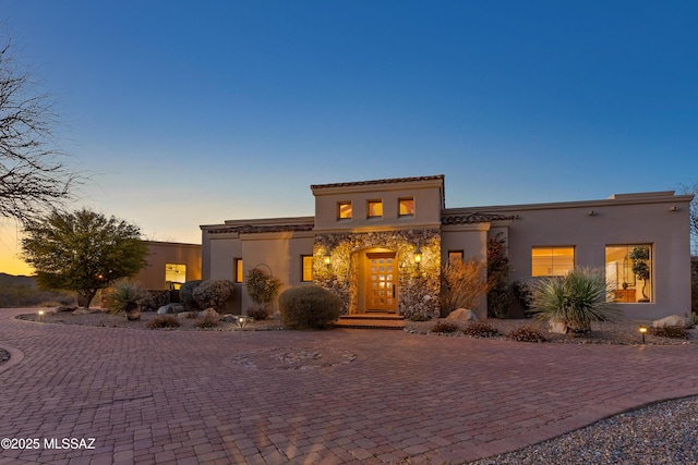 mediterranean / spanish house with decorative driveway, stone siding, and stucco siding