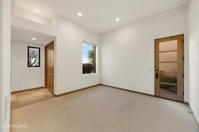 empty room featuring recessed lighting, baseboards, and light colored carpet