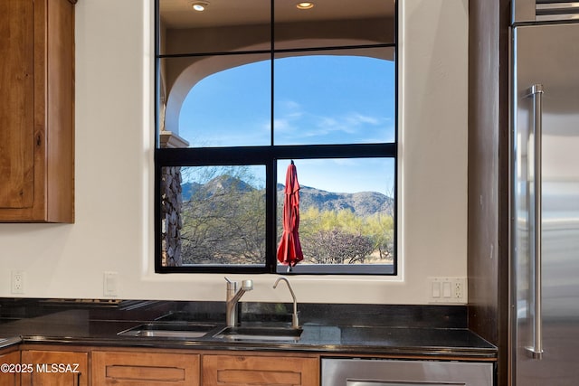 kitchen featuring high end refrigerator, a mountain view, brown cabinets, and a sink