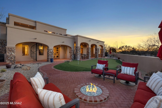 back of property featuring a patio, an outdoor living space with a fire pit, and stucco siding