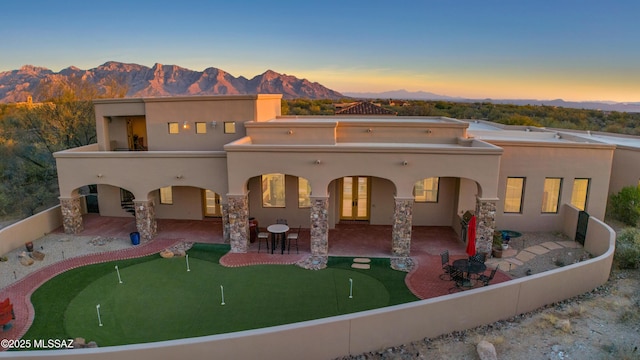 rear view of property featuring stucco siding, a mountain view, and a patio