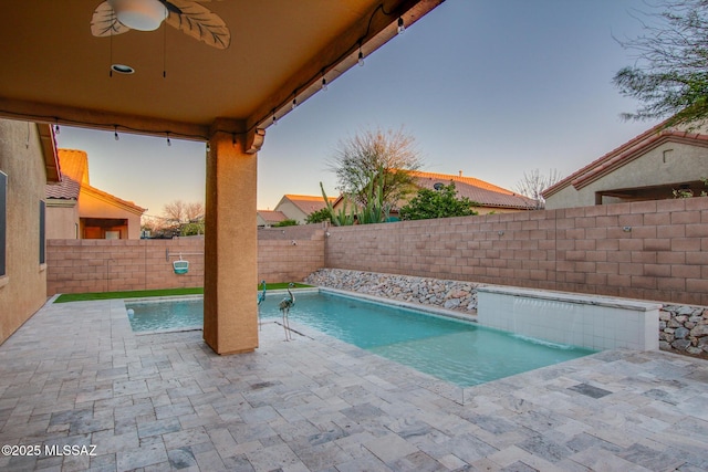 pool at dusk with a fenced in pool, a fenced backyard, a patio, and ceiling fan