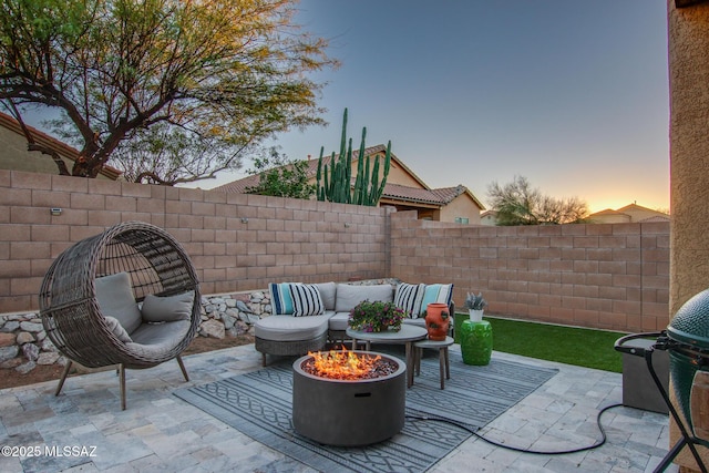 patio terrace at dusk featuring an outdoor living space with a fire pit, area for grilling, and fence