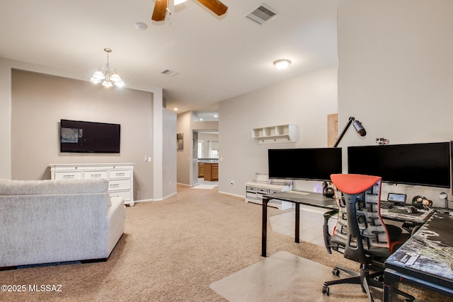 carpeted home office featuring ceiling fan with notable chandelier, visible vents, and baseboards