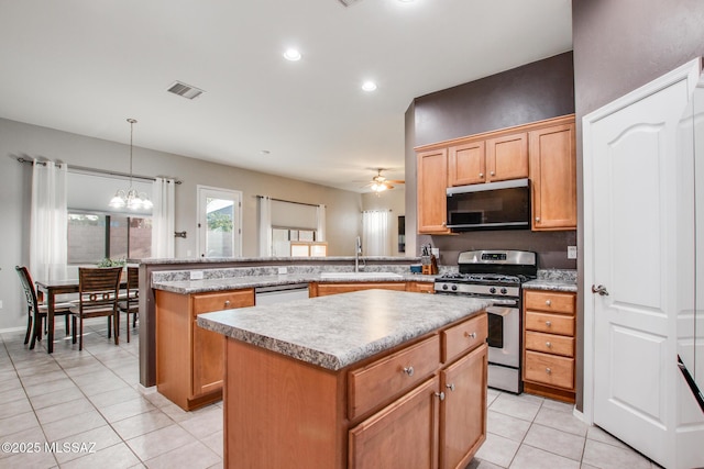 kitchen featuring stainless steel range with gas stovetop, a center island, a peninsula, light countertops, and a sink