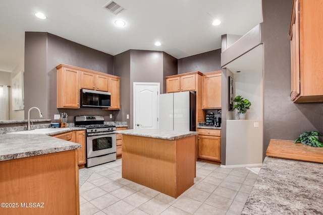 kitchen with light tile patterned floors, stainless steel appliances, a sink, visible vents, and a center island