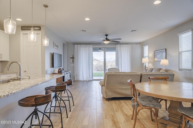living area featuring light wood-style floors, visible vents, plenty of natural light, and ceiling fan