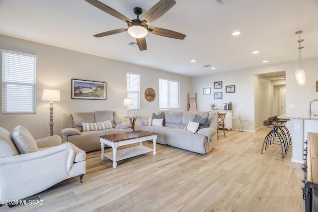 living room featuring light wood-style flooring, recessed lighting, a ceiling fan, baseboards, and visible vents