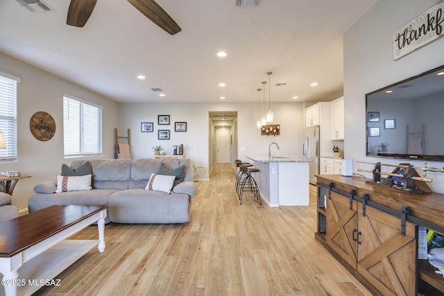 living area with light wood-type flooring, visible vents, and recessed lighting