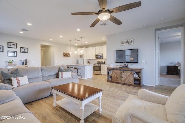 living room featuring light wood-type flooring, visible vents, and recessed lighting