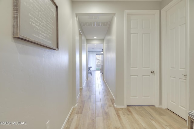 hallway with light wood-type flooring, baseboards, and visible vents