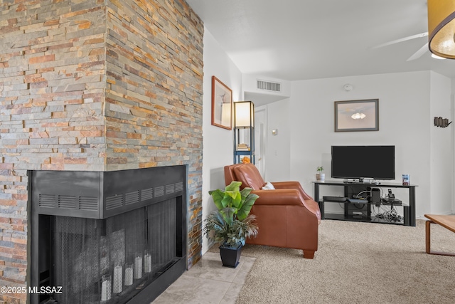 living room with light carpet, visible vents, and a stone fireplace