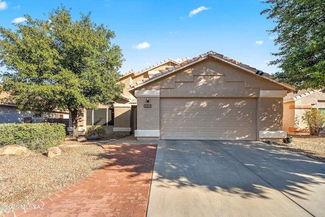 view of front of house featuring a garage, a tiled roof, concrete driveway, and stucco siding