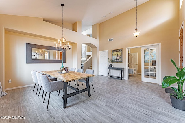 dining space with arched walkways, visible vents, stairway, wood finished floors, and baseboards