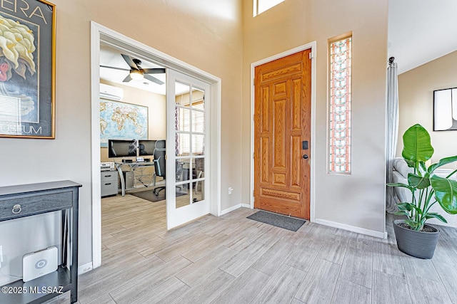 foyer with an AC wall unit, french doors, wood finish floors, and baseboards