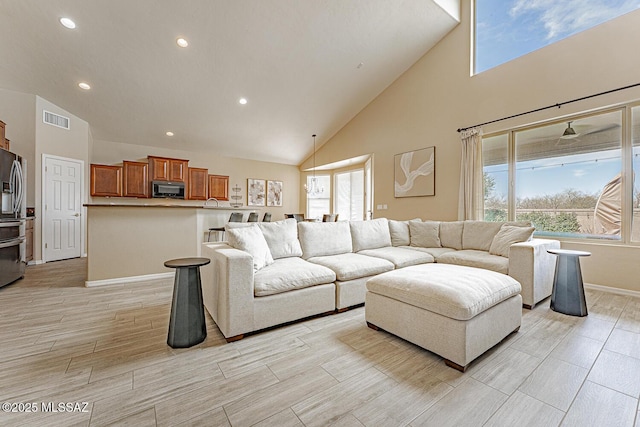 living room with a healthy amount of sunlight, high vaulted ceiling, and visible vents