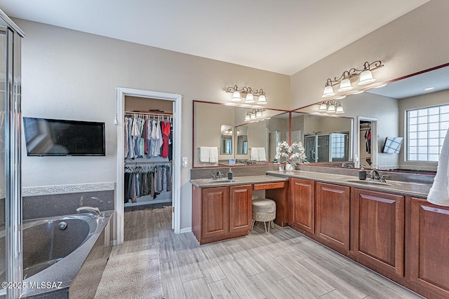 bathroom with double vanity, wood finished floors, a sink, and a bath