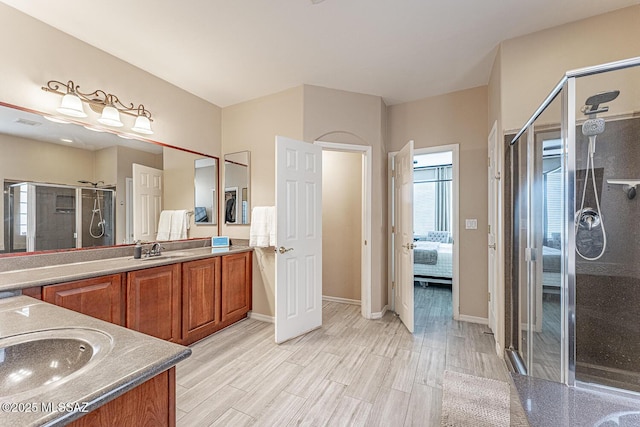 ensuite bathroom featuring visible vents, a stall shower, vanity, ensuite bath, and wood finished floors