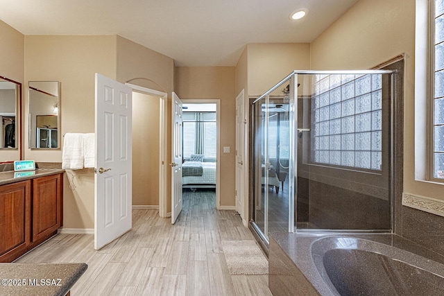 ensuite bathroom with wood finished floors, a shower stall, vanity, and connected bathroom