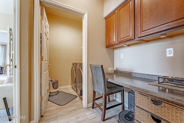 office space with light wood-type flooring, built in desk, and baseboards