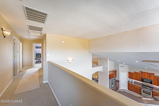 hallway featuring light carpet, baseboards, and visible vents