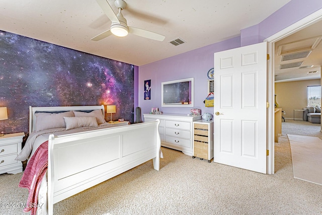 bedroom with light carpet, wallpapered walls, visible vents, ceiling fan, and an accent wall