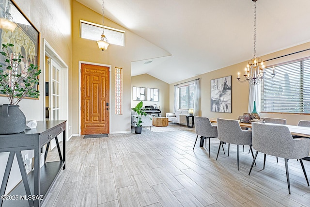 entrance foyer with vaulted ceiling, wood finish floors, a chandelier, and baseboards