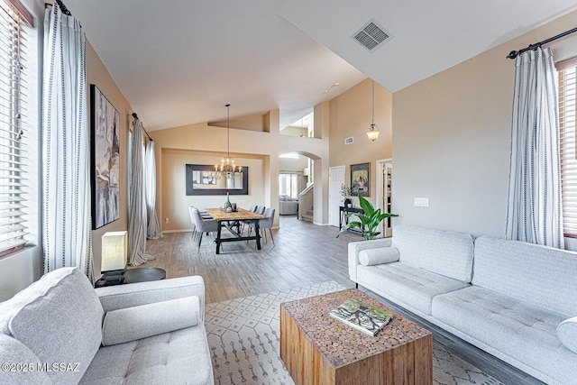 living room with arched walkways, visible vents, a chandelier, wood finished floors, and high vaulted ceiling