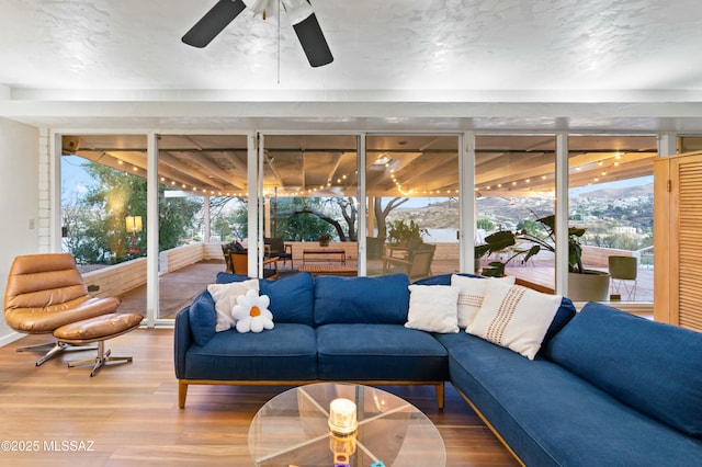 sunroom / solarium with a healthy amount of sunlight, a mountain view, and ceiling fan