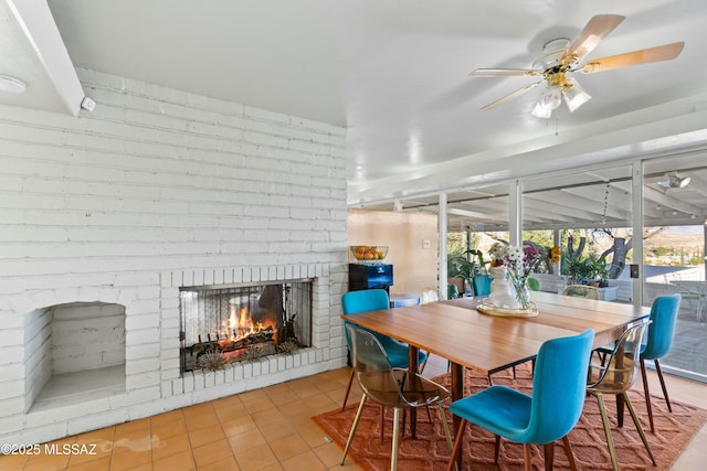 tiled dining space featuring a fireplace and a ceiling fan