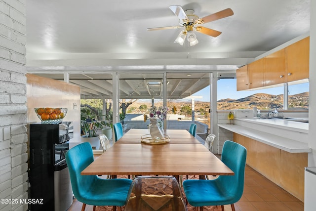 sunroom / solarium featuring a ceiling fan, a wealth of natural light, and a mountain view