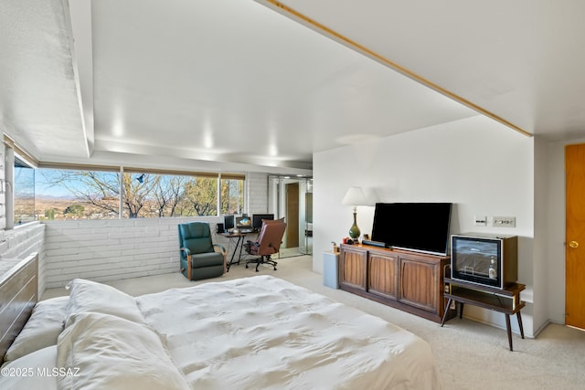 bedroom with light colored carpet and brick wall