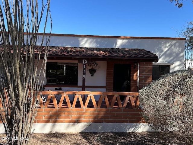 view of exterior entry featuring a porch and a tile roof