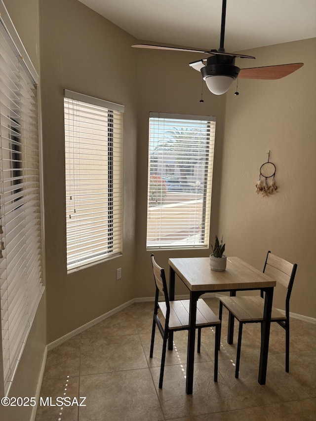 tiled dining space with a ceiling fan, baseboards, and a wealth of natural light