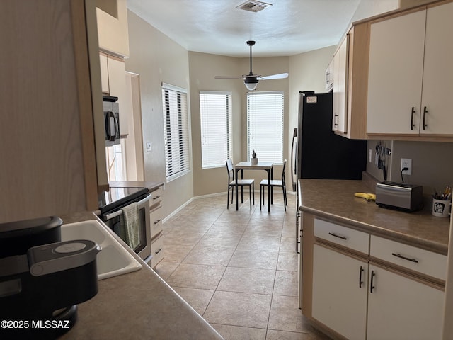 kitchen with light tile patterned floors, visible vents, appliances with stainless steel finishes, a ceiling fan, and baseboards