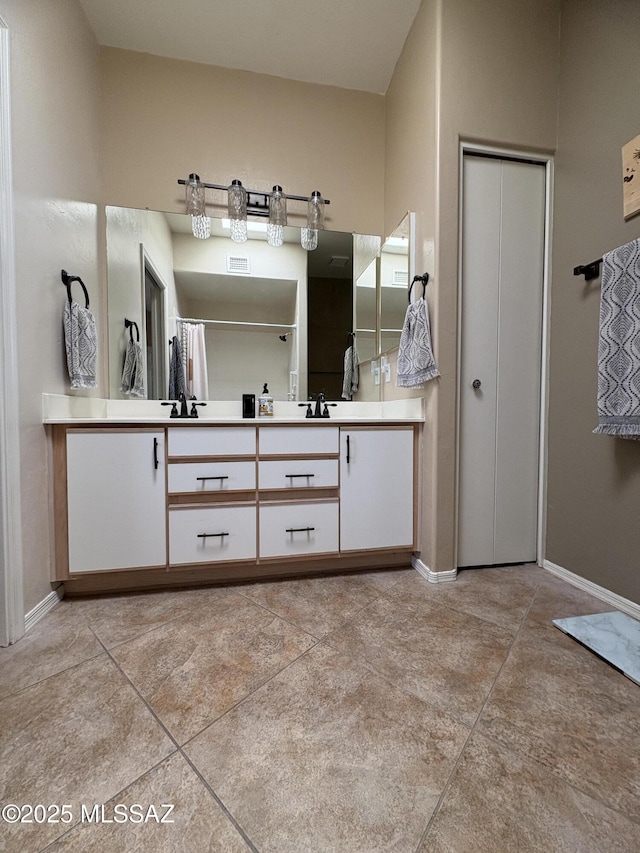 bathroom featuring double vanity, visible vents, and baseboards