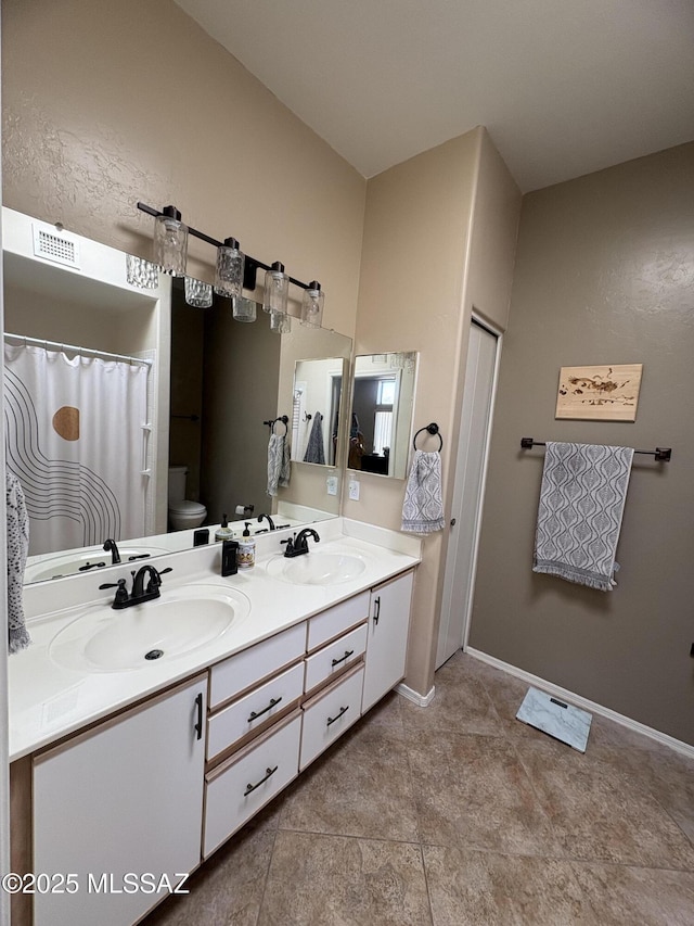 full bathroom with toilet, double vanity, and a sink