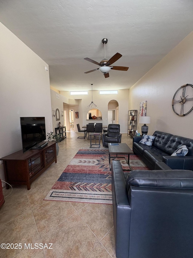 living area with a ceiling fan and arched walkways