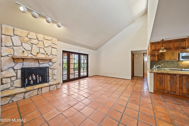 interior space with french doors, stainless steel microwave, a fireplace, and light tile patterned floors