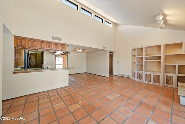 unfurnished living room with a ceiling fan, visible vents, high vaulted ceiling, and light tile patterned flooring