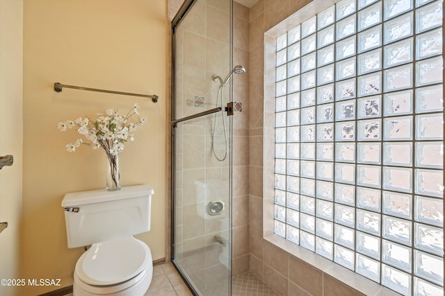 full bath with tile patterned flooring, a tile shower, and toilet