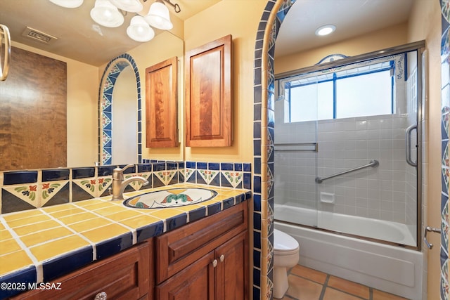 bathroom with tile patterned flooring, toilet, bath / shower combo with glass door, vanity, and visible vents