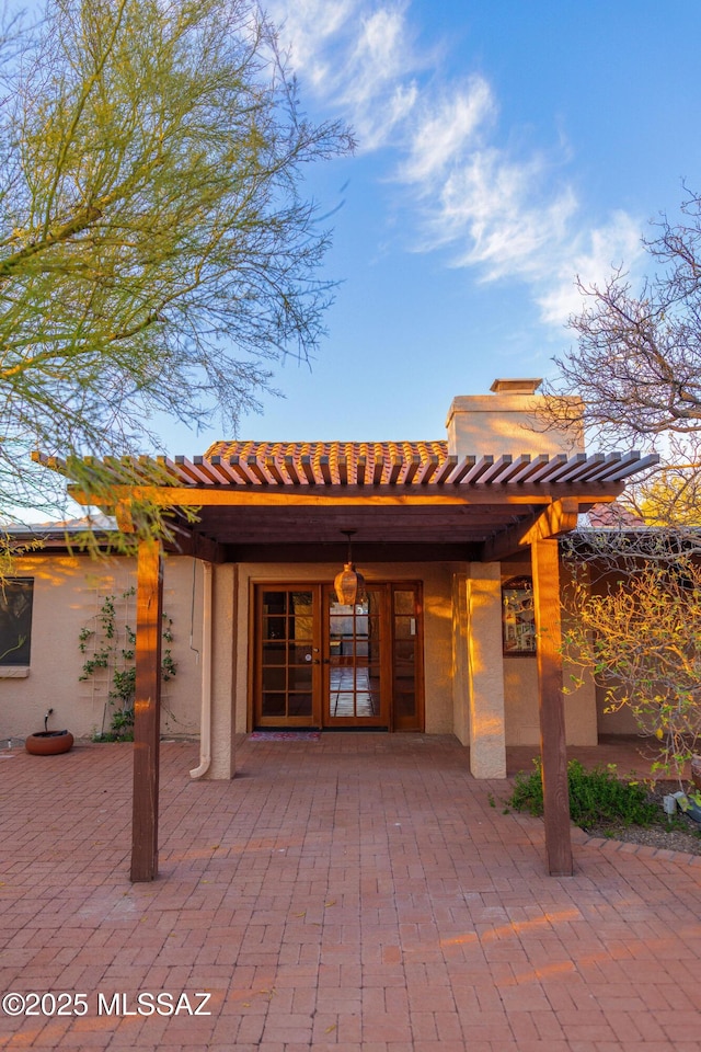 entrance to property featuring french doors, a patio area, and a pergola