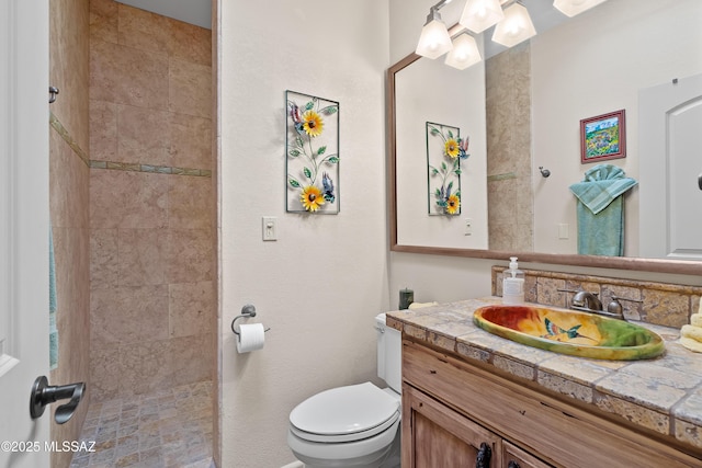 bathroom with tiled shower, vanity, and toilet