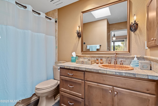 full bathroom featuring a textured wall, toilet, a skylight, vanity, and visible vents