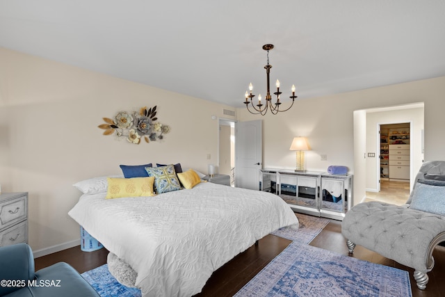 bedroom featuring visible vents, a notable chandelier, baseboards, and wood finished floors