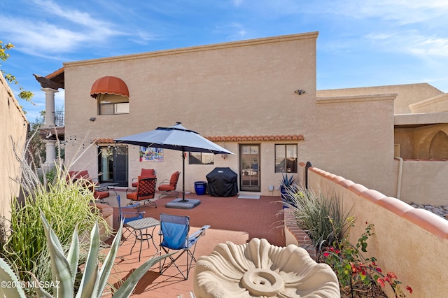 rear view of house featuring a patio area, fence, and stucco siding