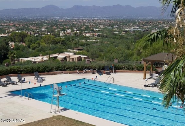 community pool featuring a patio, fence, and a mountain view